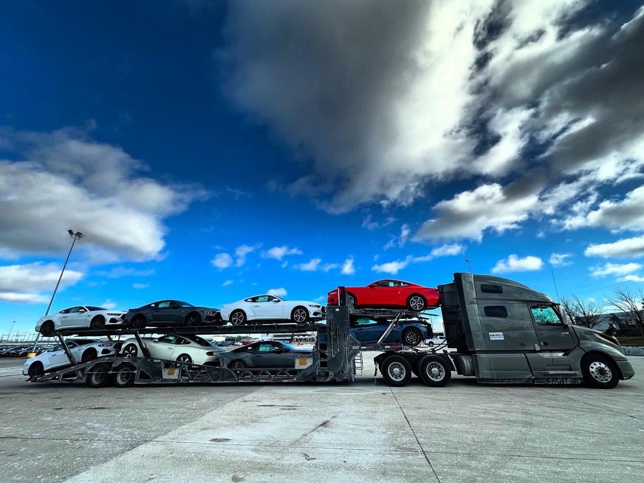 Complete Dharma Express truck and loaded auto carrier beneath a dramatic sky